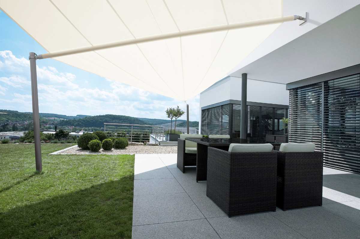 Weißes asymmetrisches Sonnensegel Weißes Sonnensegel über dem Outdoor-Bereich eines Hauses
