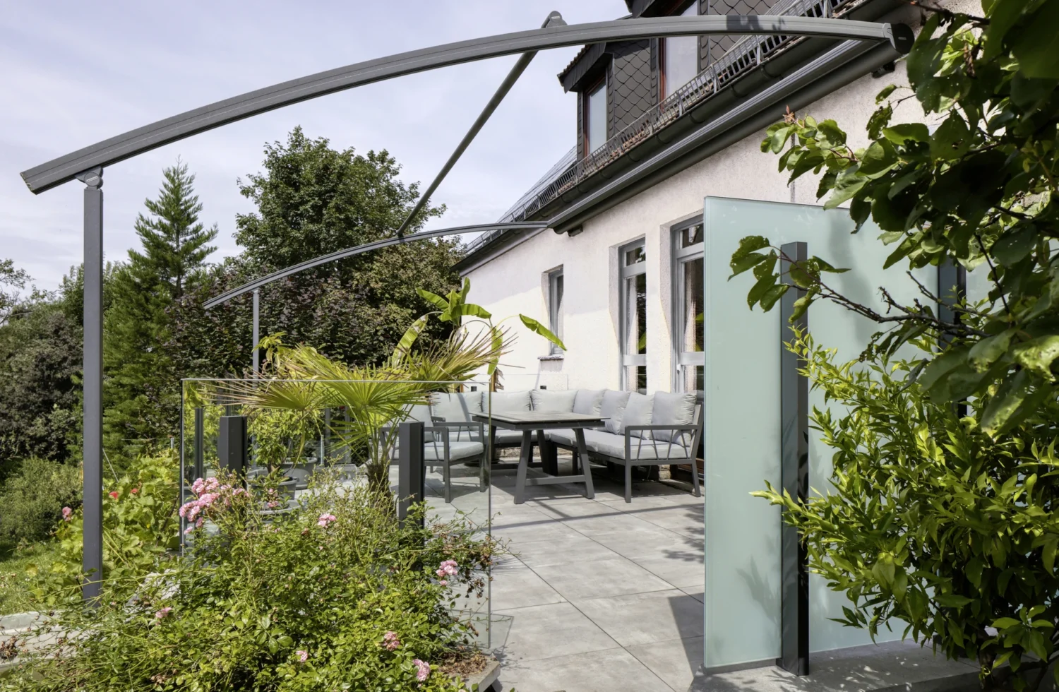 Moderne Terrasse mit Glasgeländer und Gartenmöbeln